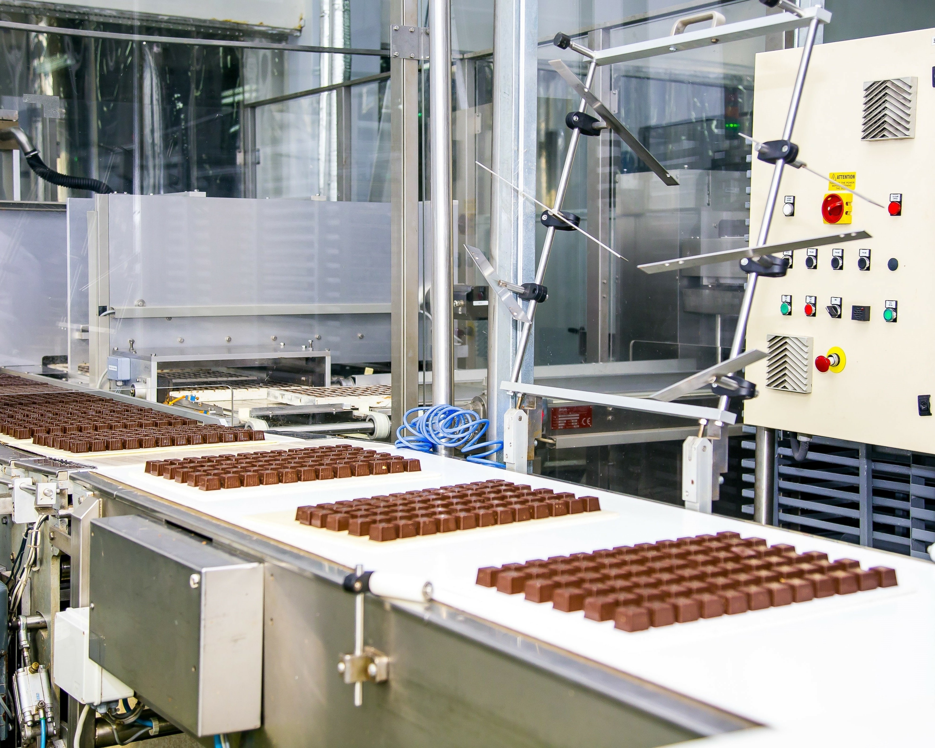 Chocolate on a conveyor belt being sorted into set amounts by a machine.