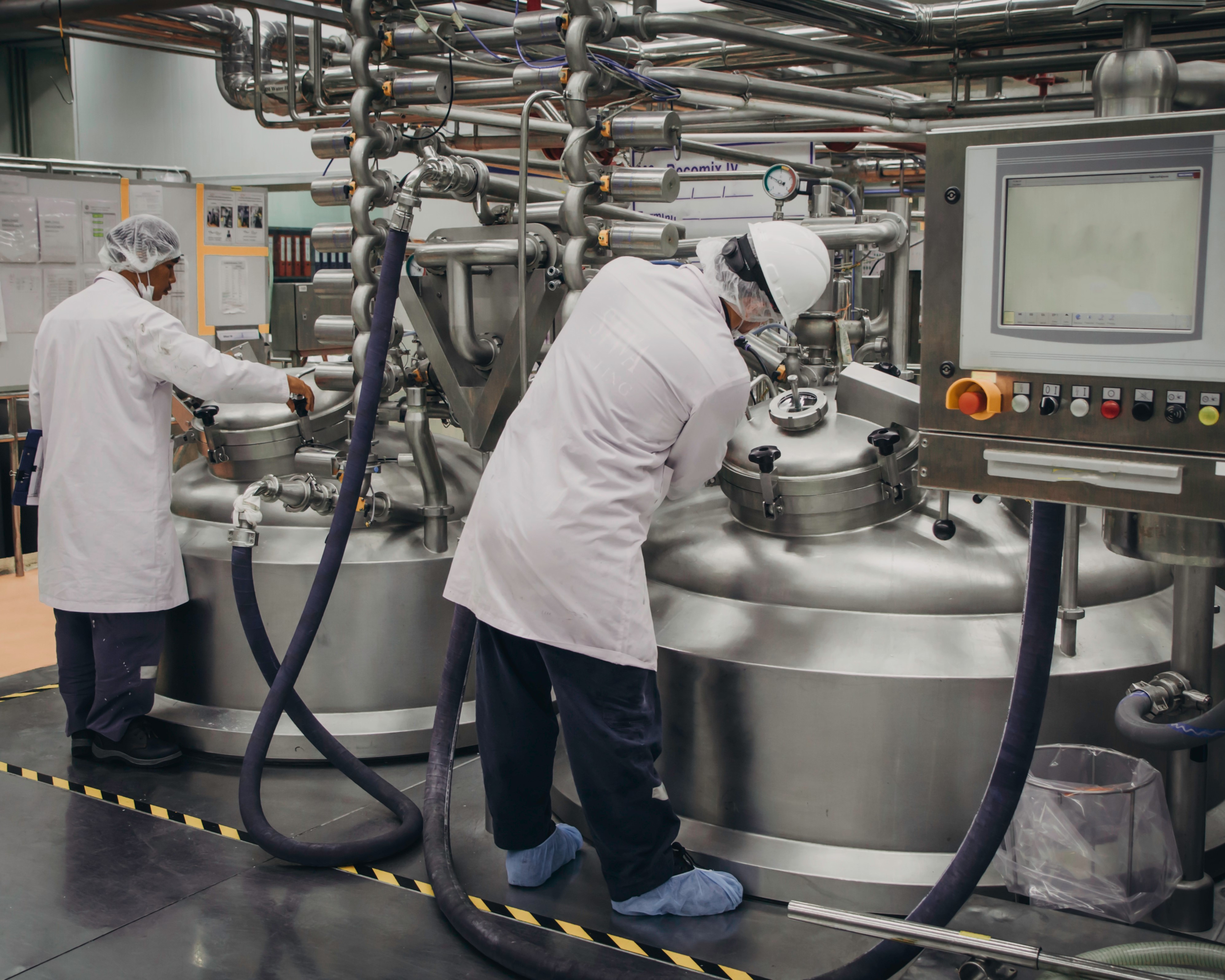 Two workers inspecting large pieces of machinery and piping.