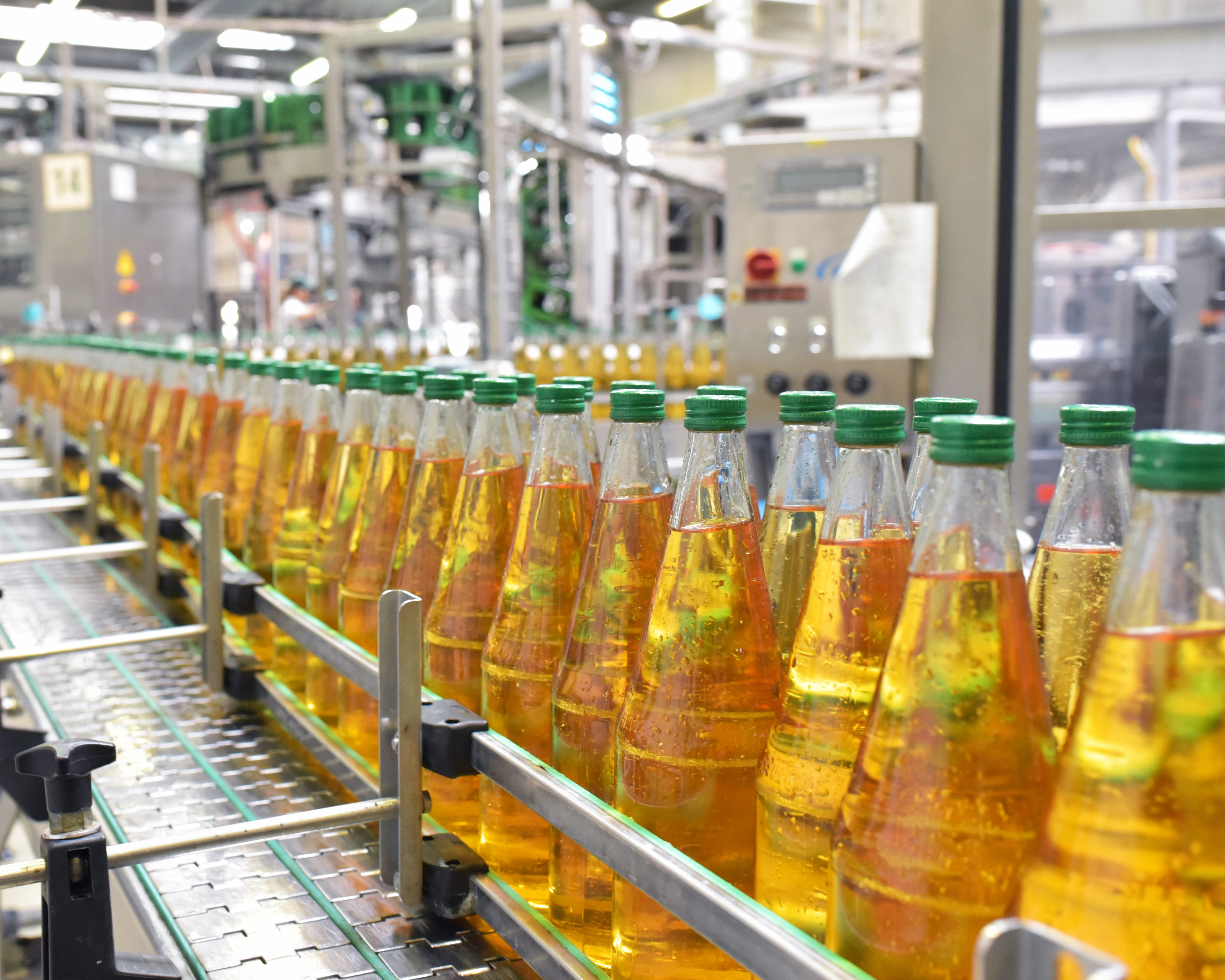 Bottling line surrounded by machinery on a conveyor belt.